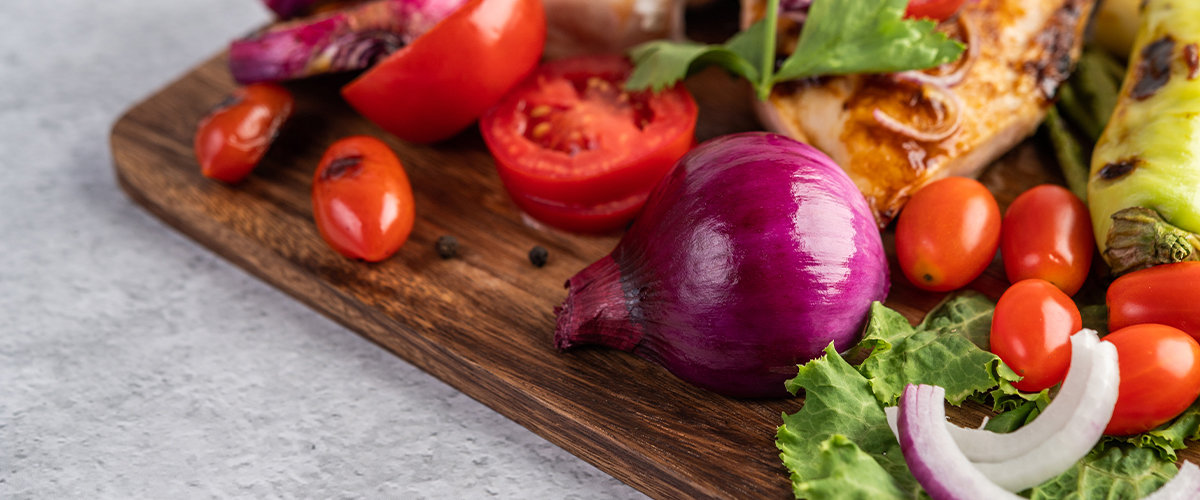 Half of an onion face down on a cutting board with grilled meat